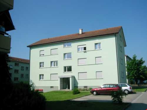 4 story house, green paint, brown roof, red bench, red car, silver car, small garden, several windows
