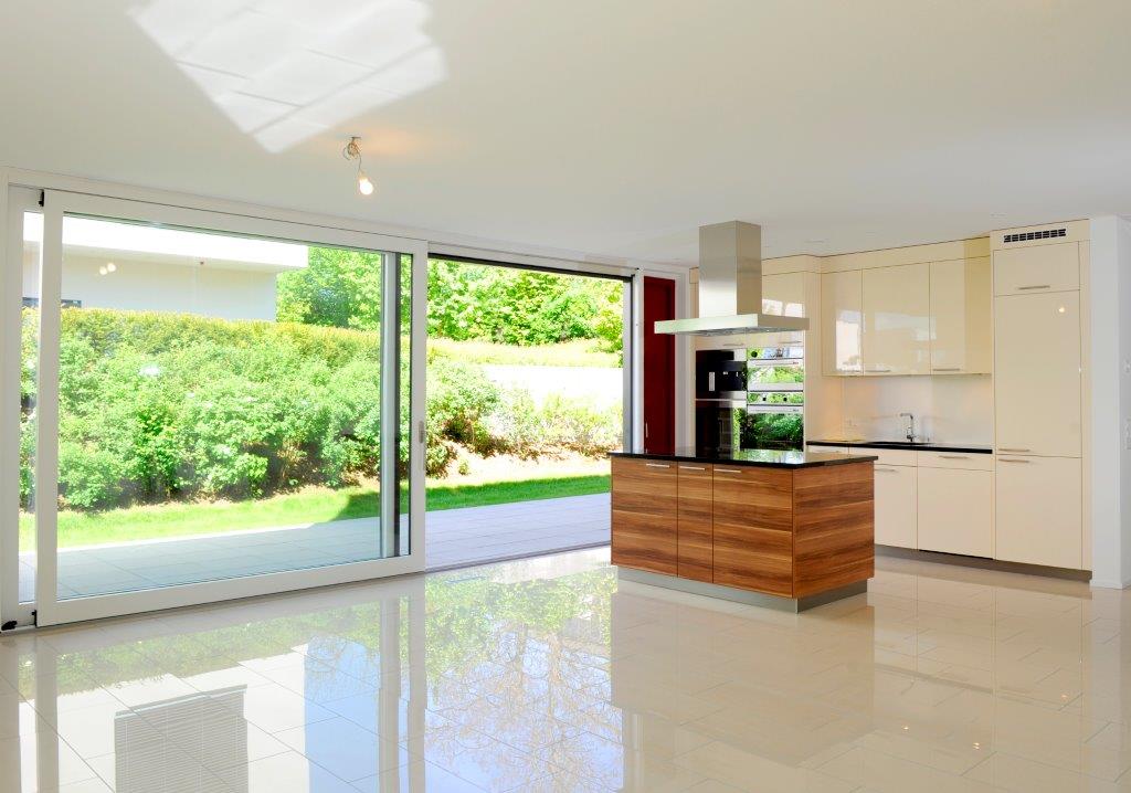 white tiled floor, wooden kitchen island, stainless steel stove and chimney, white cupboards, double sliding glass doors, modern design