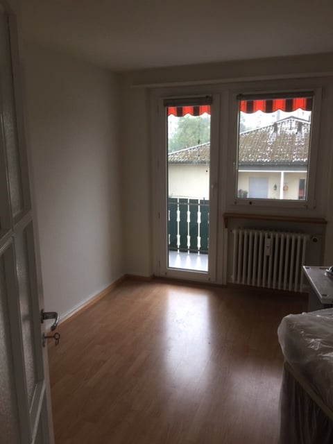 empty room, wooden floor, sliding glass door, balcony, radiator, white walls