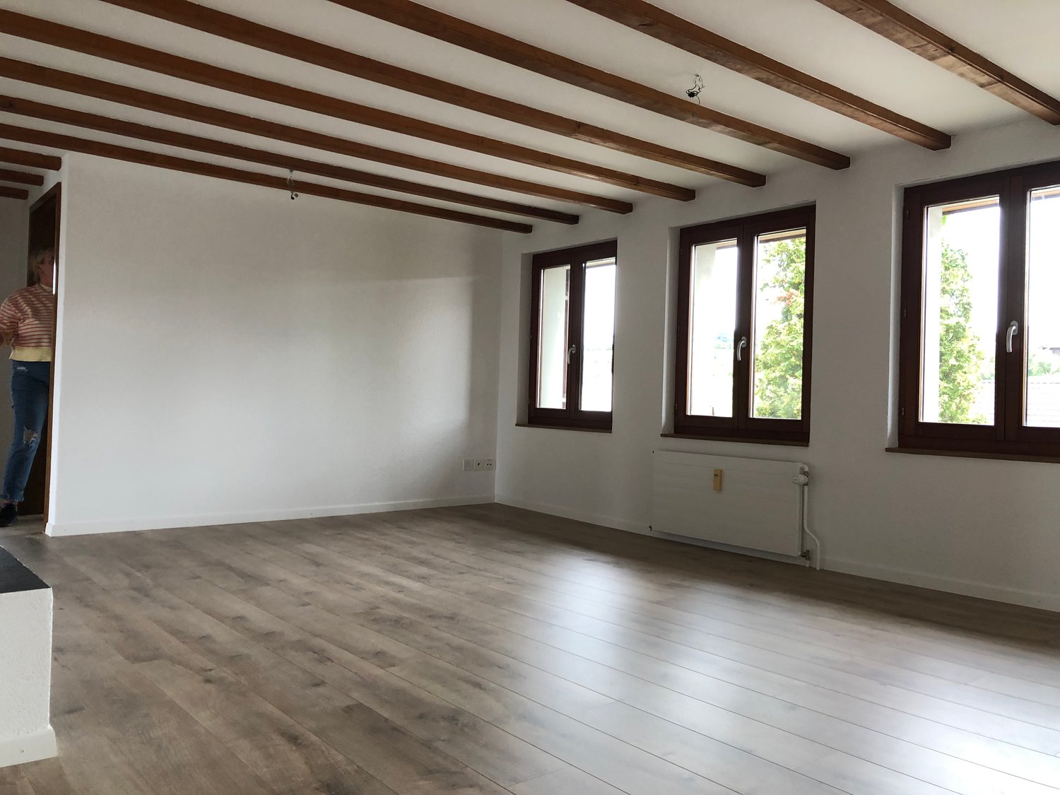 empty room, white walls, wooden floor, wooden ceiling, 3 windows, radiator