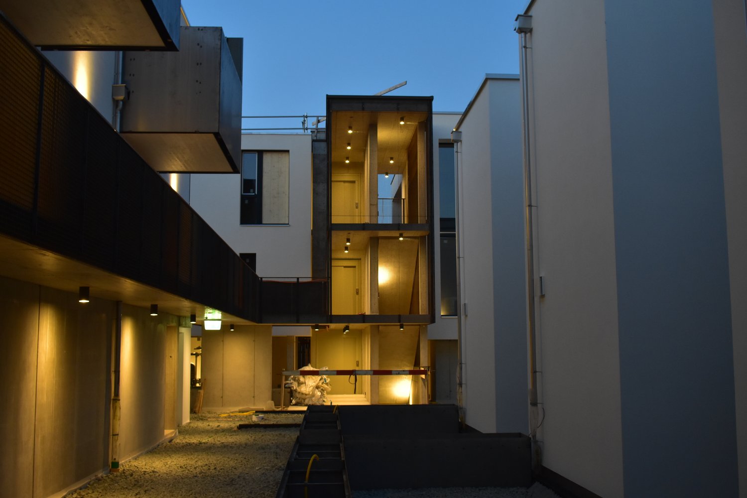 White and gray building with multiple floors, exterior stairwells, and balconies, currently under construction