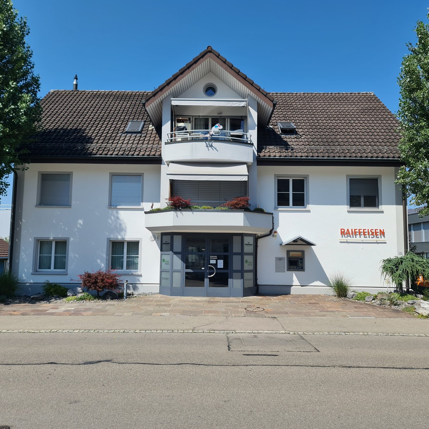 Two story house, brown roof, white walls, large balcony, glass door