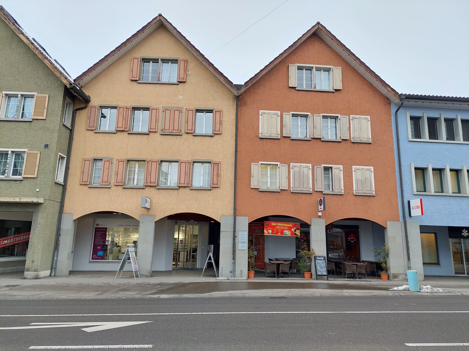 Apartment building with three floors, multiple windows, entrance, restaurant area