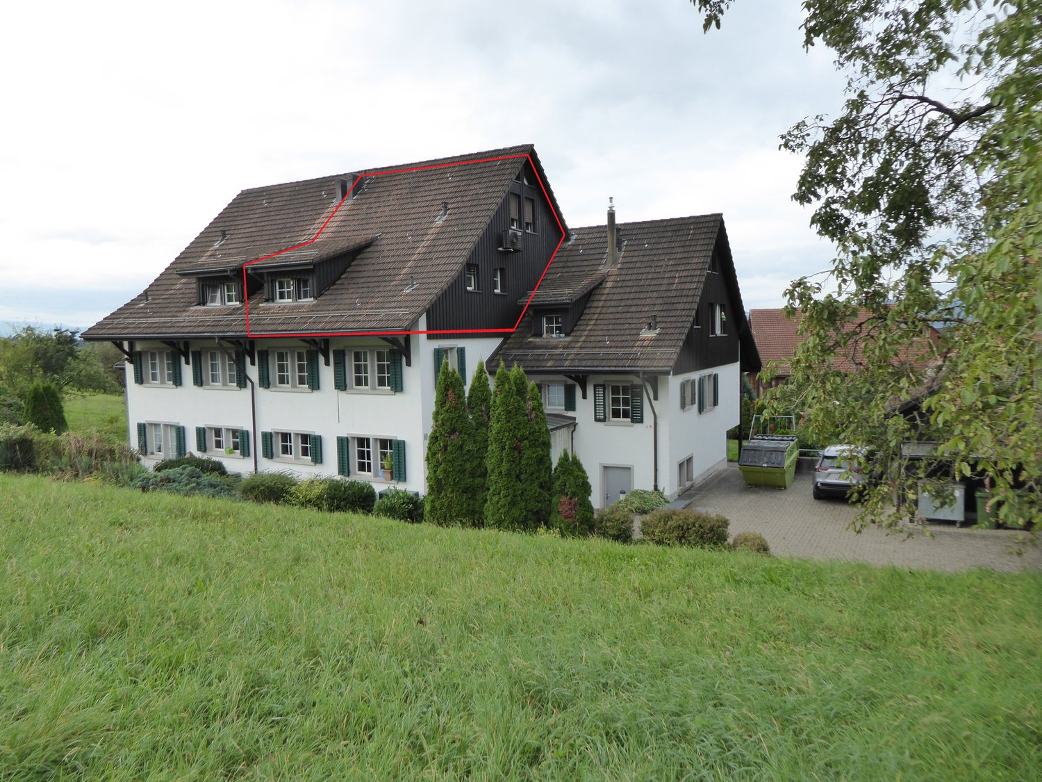 Detached house, two stories, white walls, brown roof, windows with green shutters, driveway with car, garage, grassy yard, trees