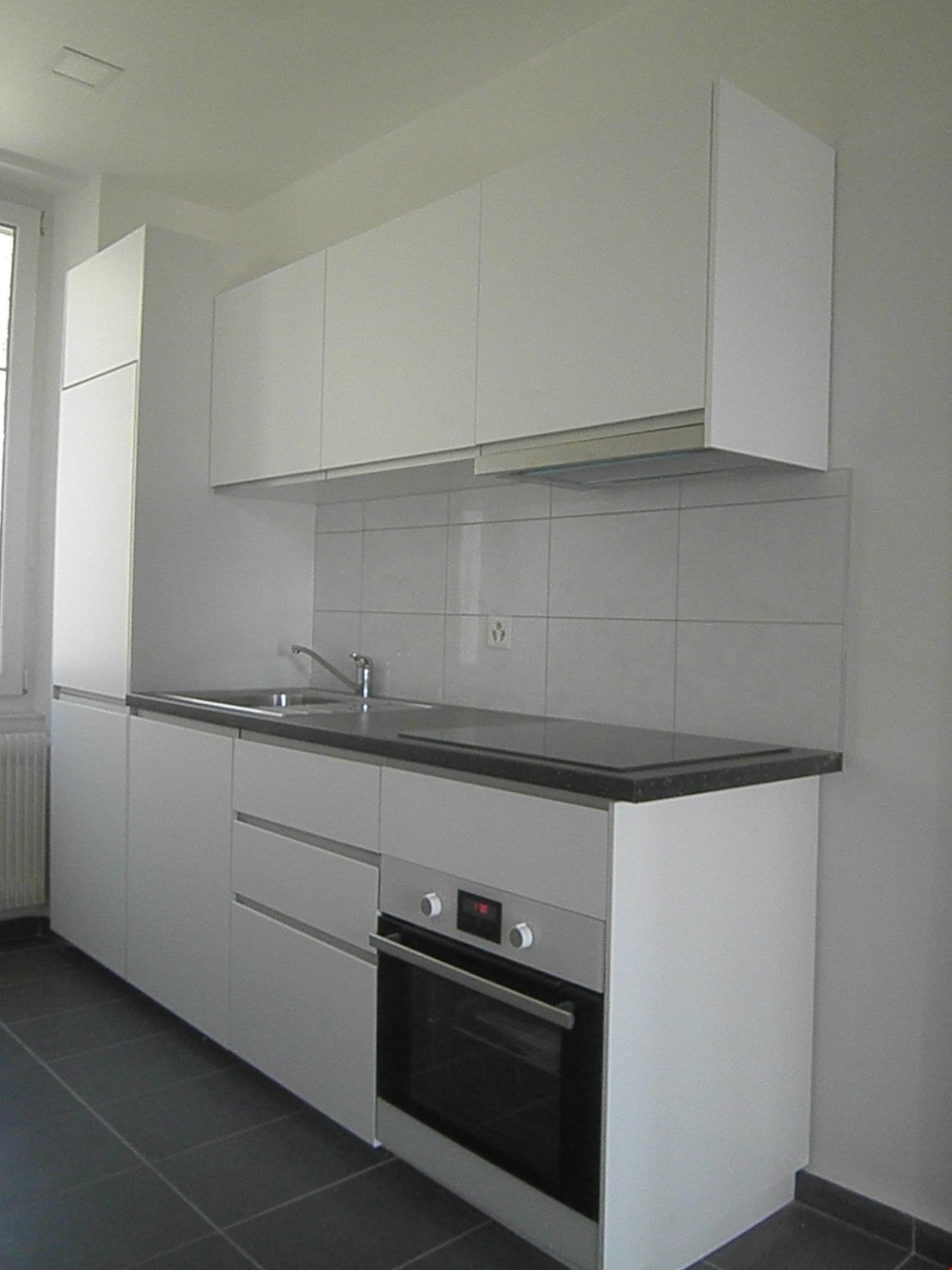 modern kitchen, white cabinets, black countertop, integrated oven and dishwasher, stainless steel sink