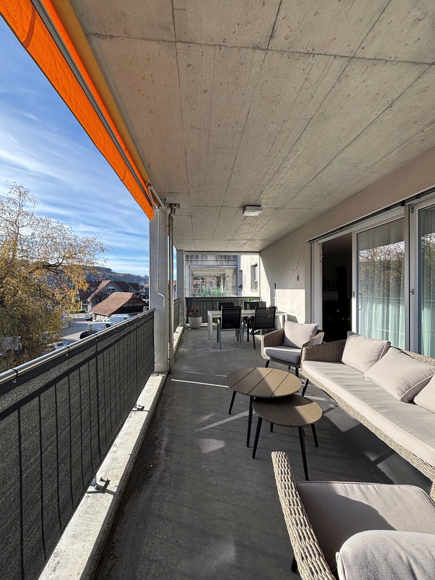 balcony, metal railing, wicker chair, table, glass door, table and chairs outside