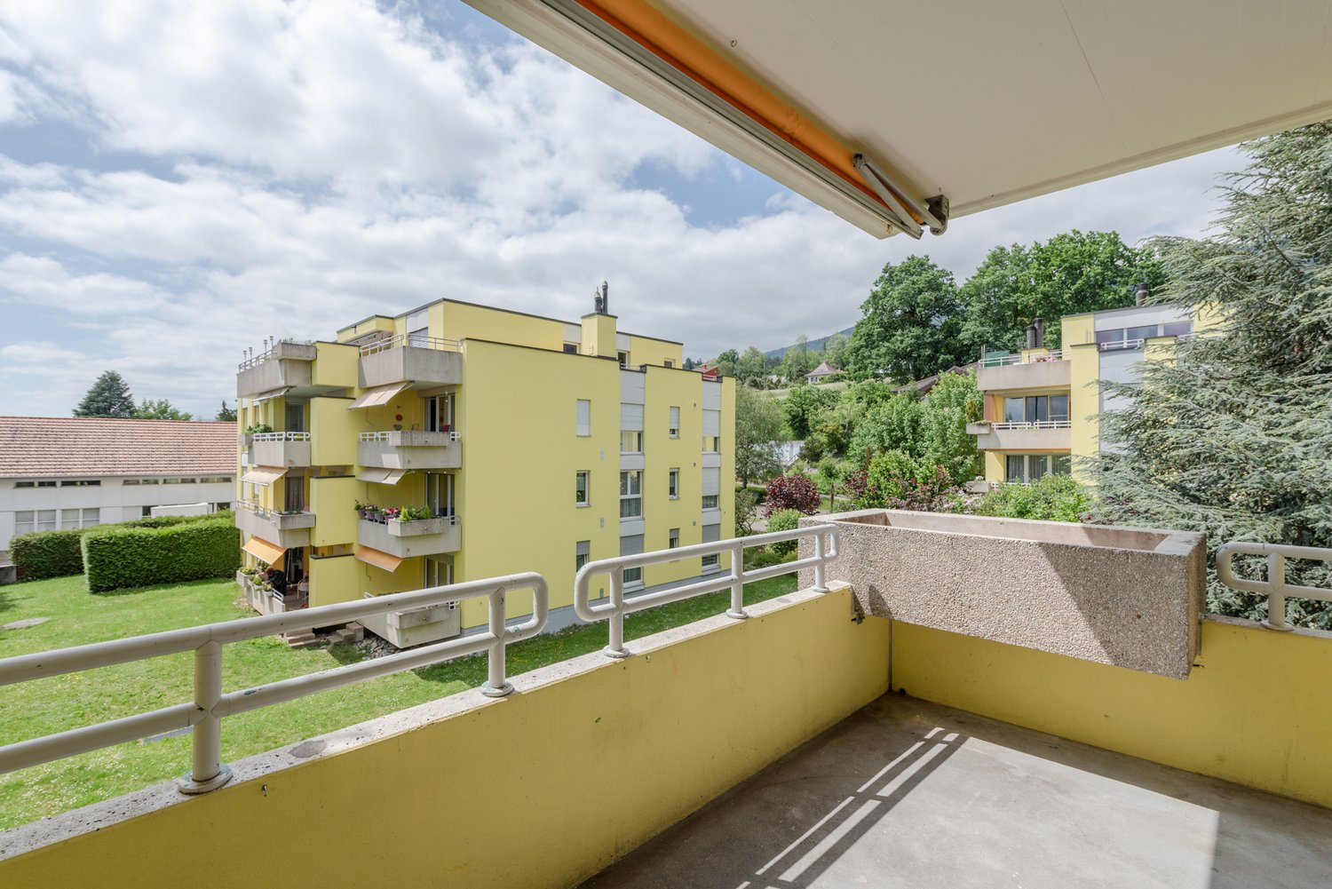 large balcony, yellow walls, white railings, garden view