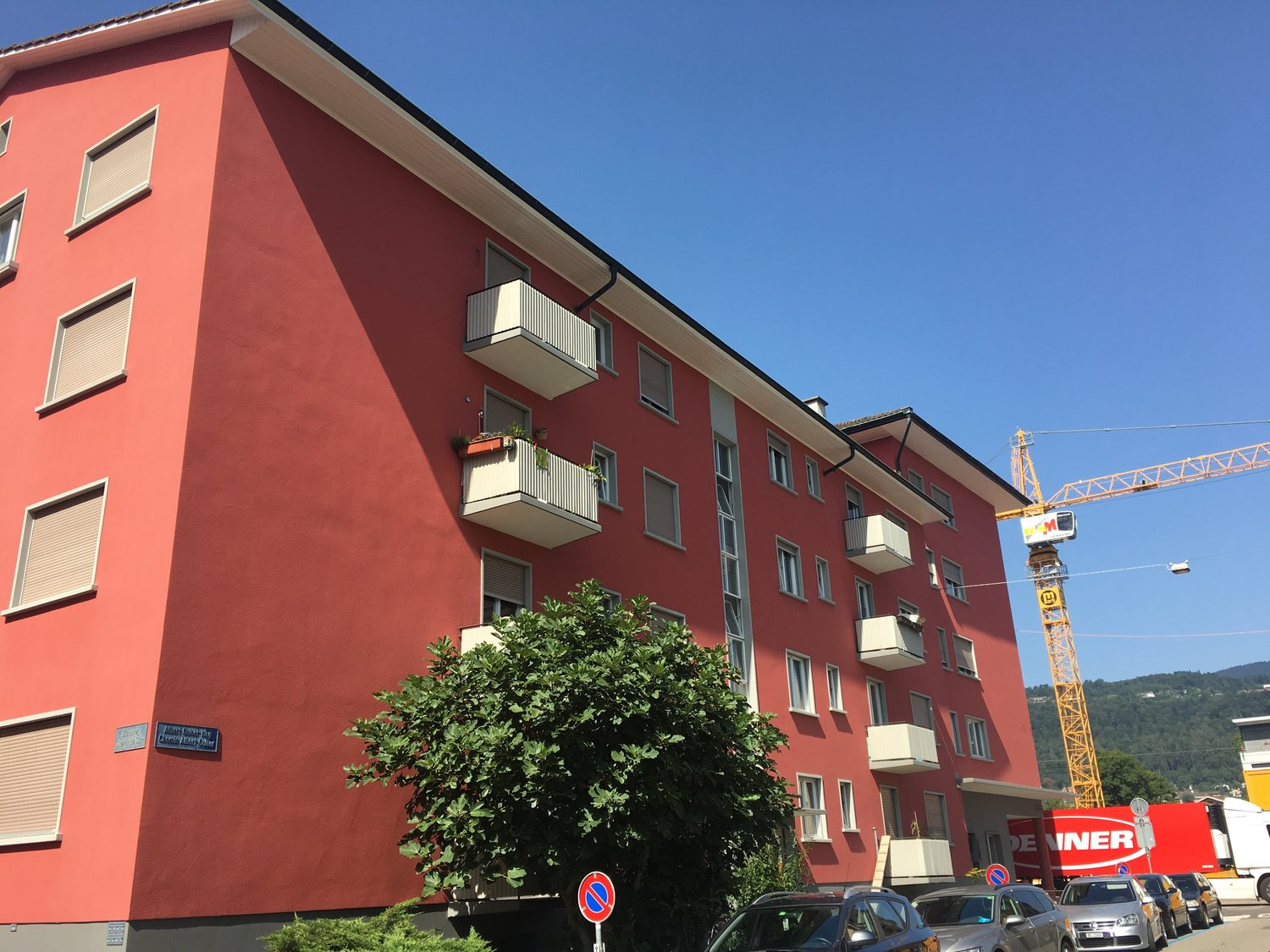 apartment building with red facade, balconies on each floor, several windows per floor