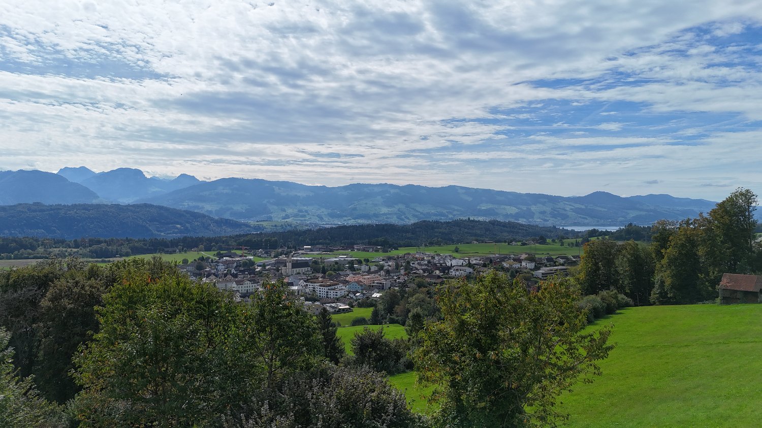 Aerial view of green valleys and mountains under a partly cloudy sky.