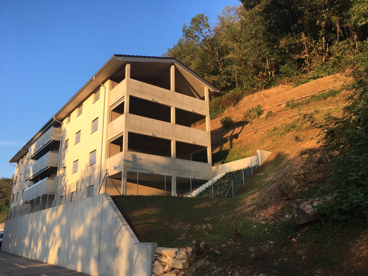 multistory building with basement, concrete facade, multiple balconies, on a slope