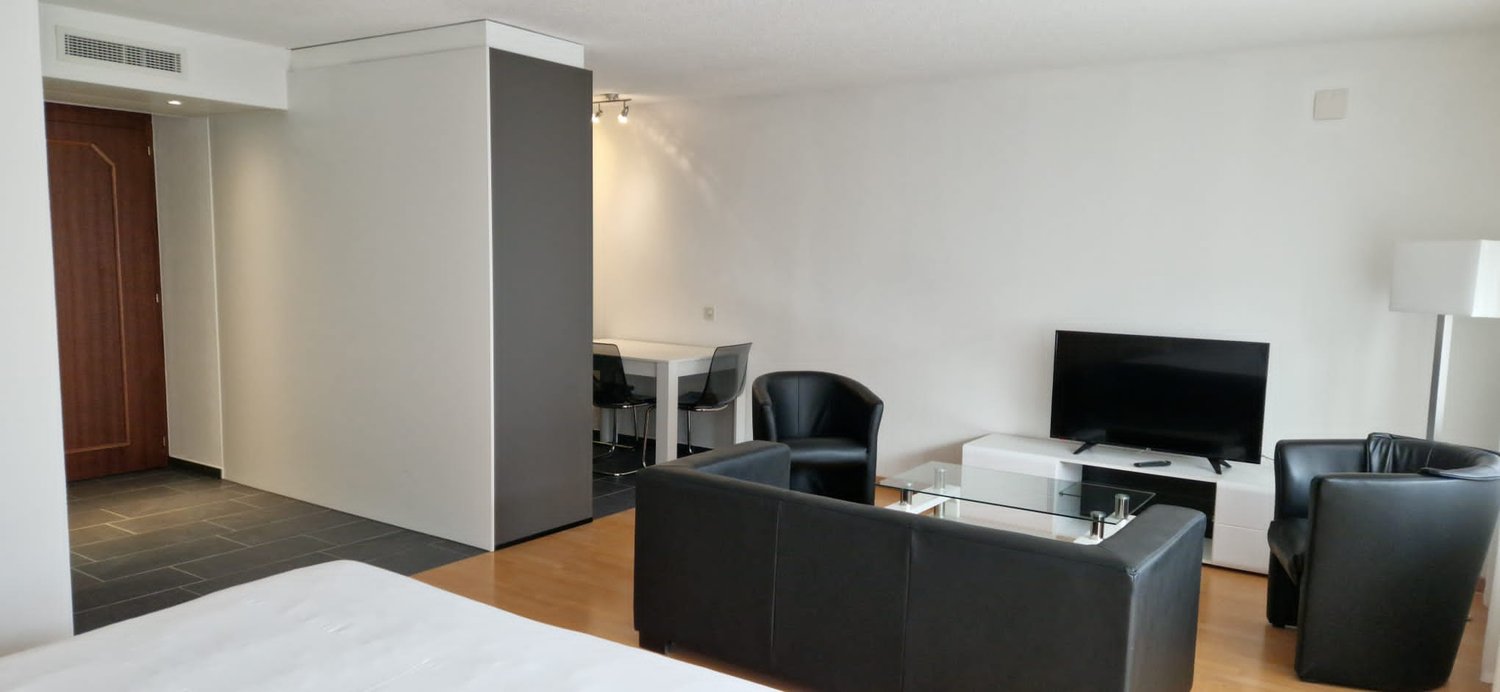 living room with sofa, armchairs, coffee table, desk, chairs, TV, lamp, tiled floor