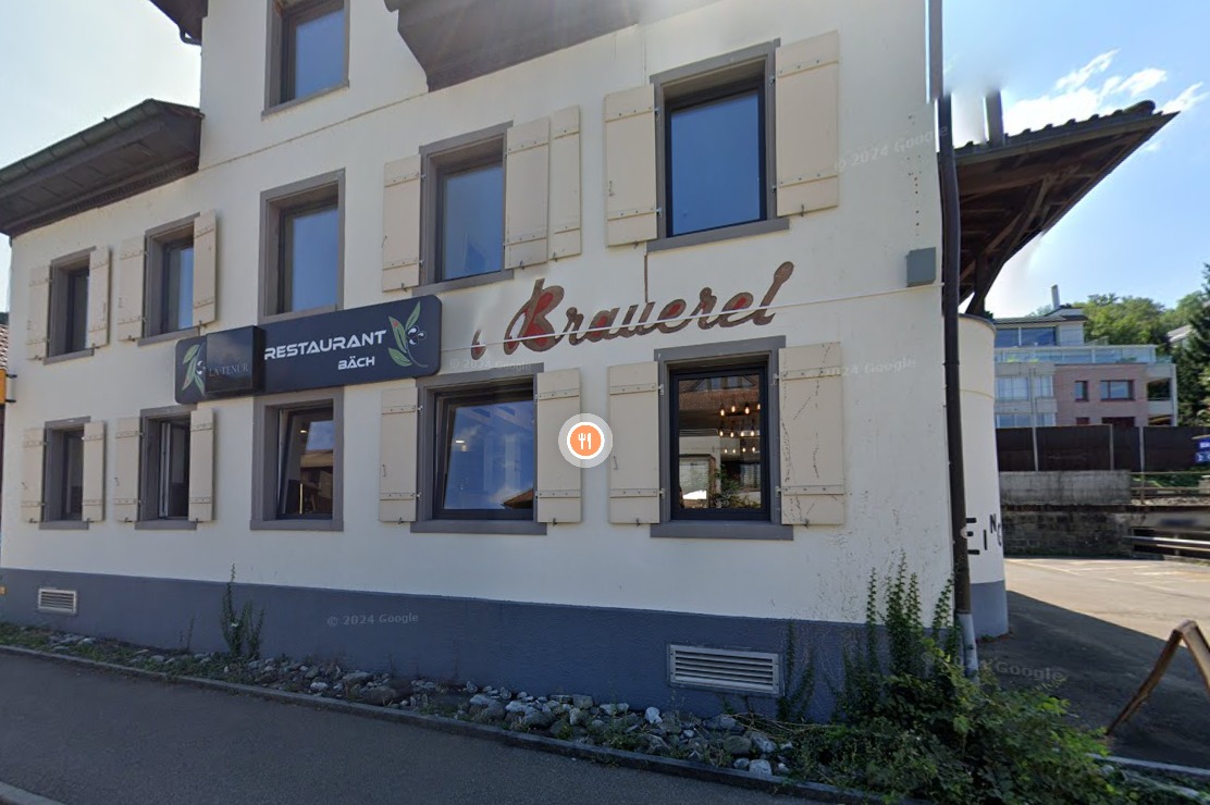 Two-story building with white walls, large windows, and wooden shutters. The restaurant name 'Krauerei' is displayed prominently on the facade.