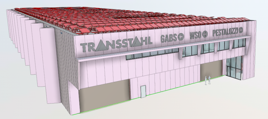 Large industrial or commercial building with a red tiled roof, the name 'Transstahl' prominently displayed on the facade, and a parking area visible in front of the building.