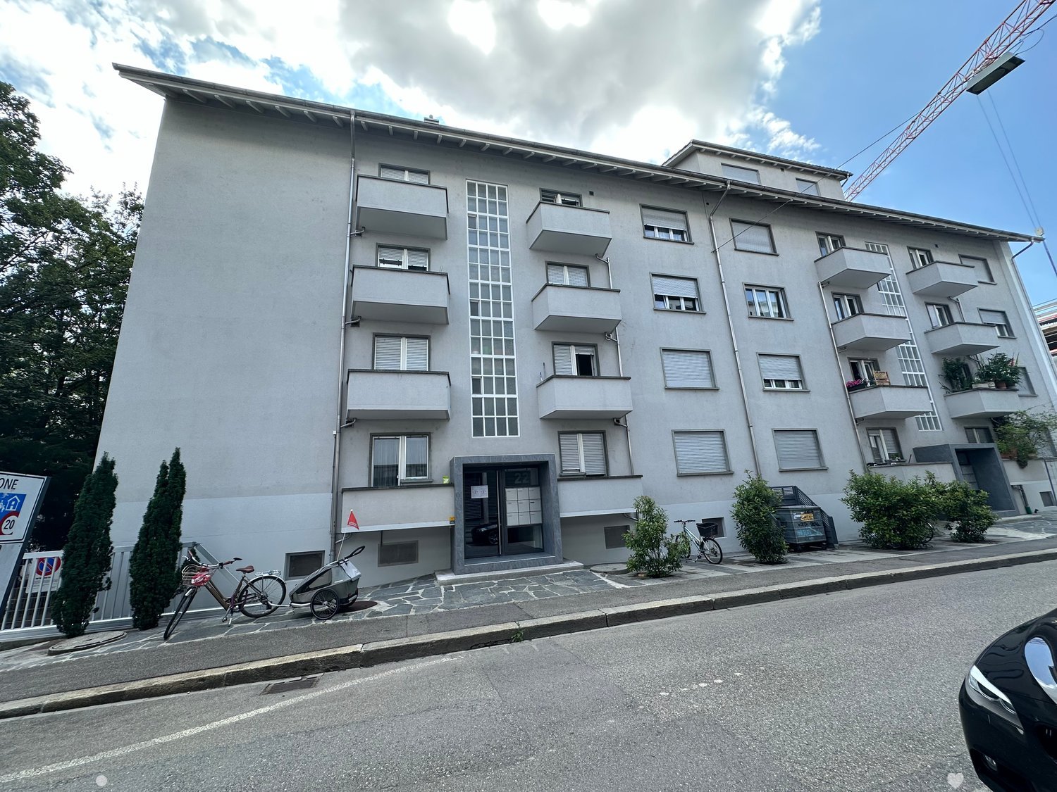 Modern apartment building with four stories and balconies, located on the street.