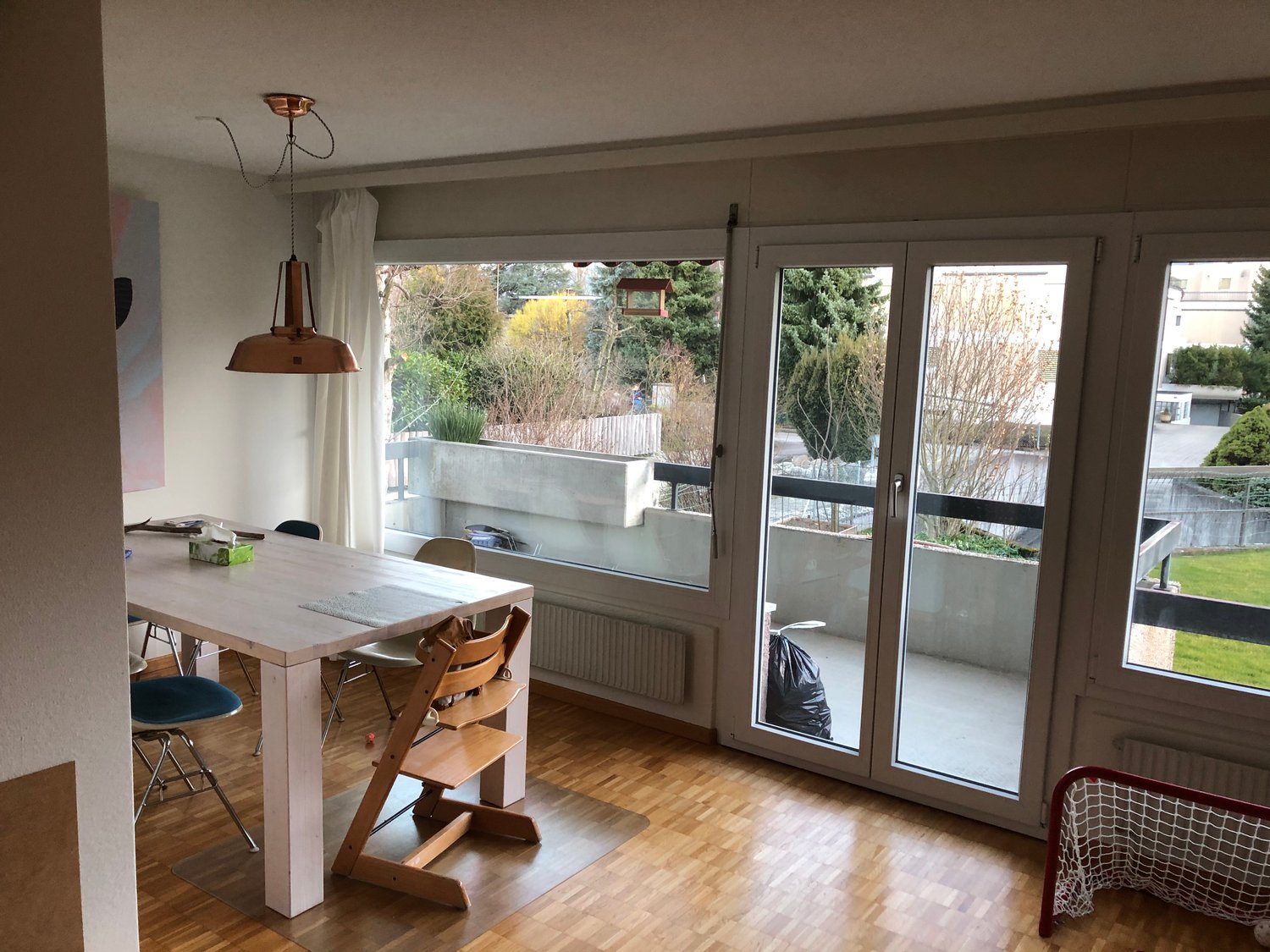 Dining room with a table, chairs, and a view of the balcony and garden