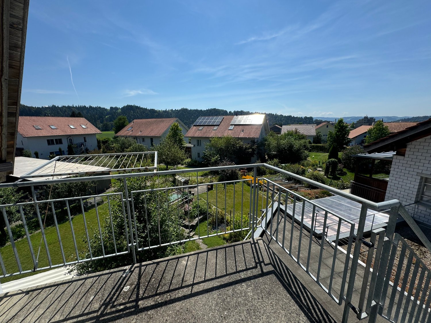 House with solar panels on the roof, surrounded by gardens and greenery