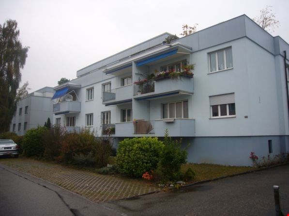 3 story white apartment building, 3 balconies, blue awnings, car parked