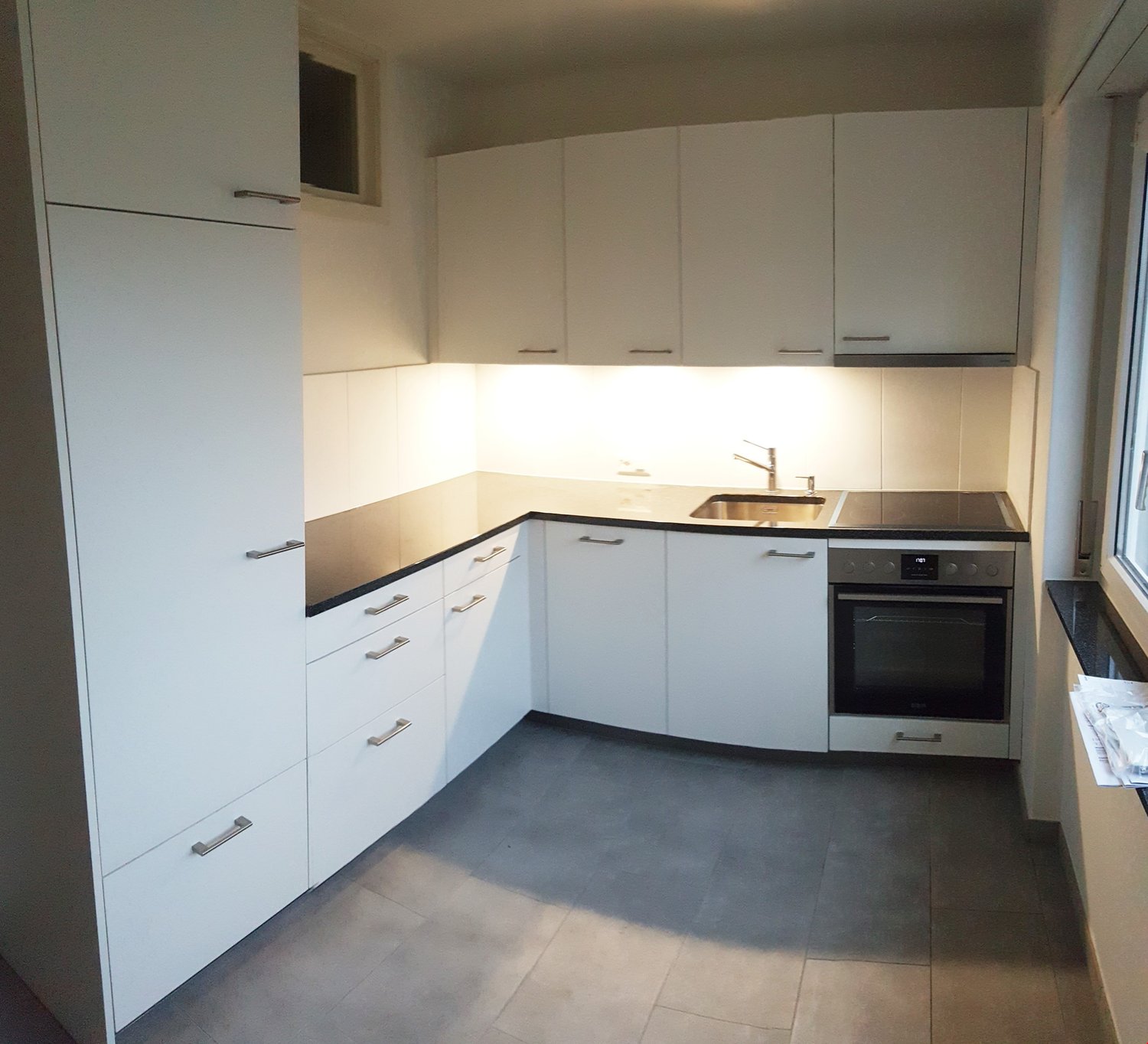Modern kitchen, clean and tidy, all white cabinets, black countertop, sink, oven, dishwasher
