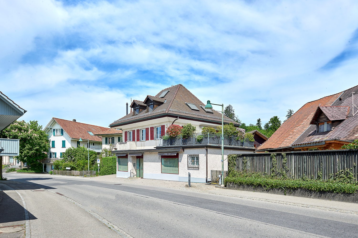 Swiss style houses, brown roofs, white walls, red shutters, balconies, green trees