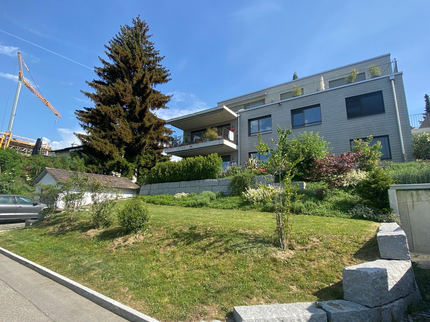 Modern 2 story house, white walls, balcony, driveway, garden, trees, parked car