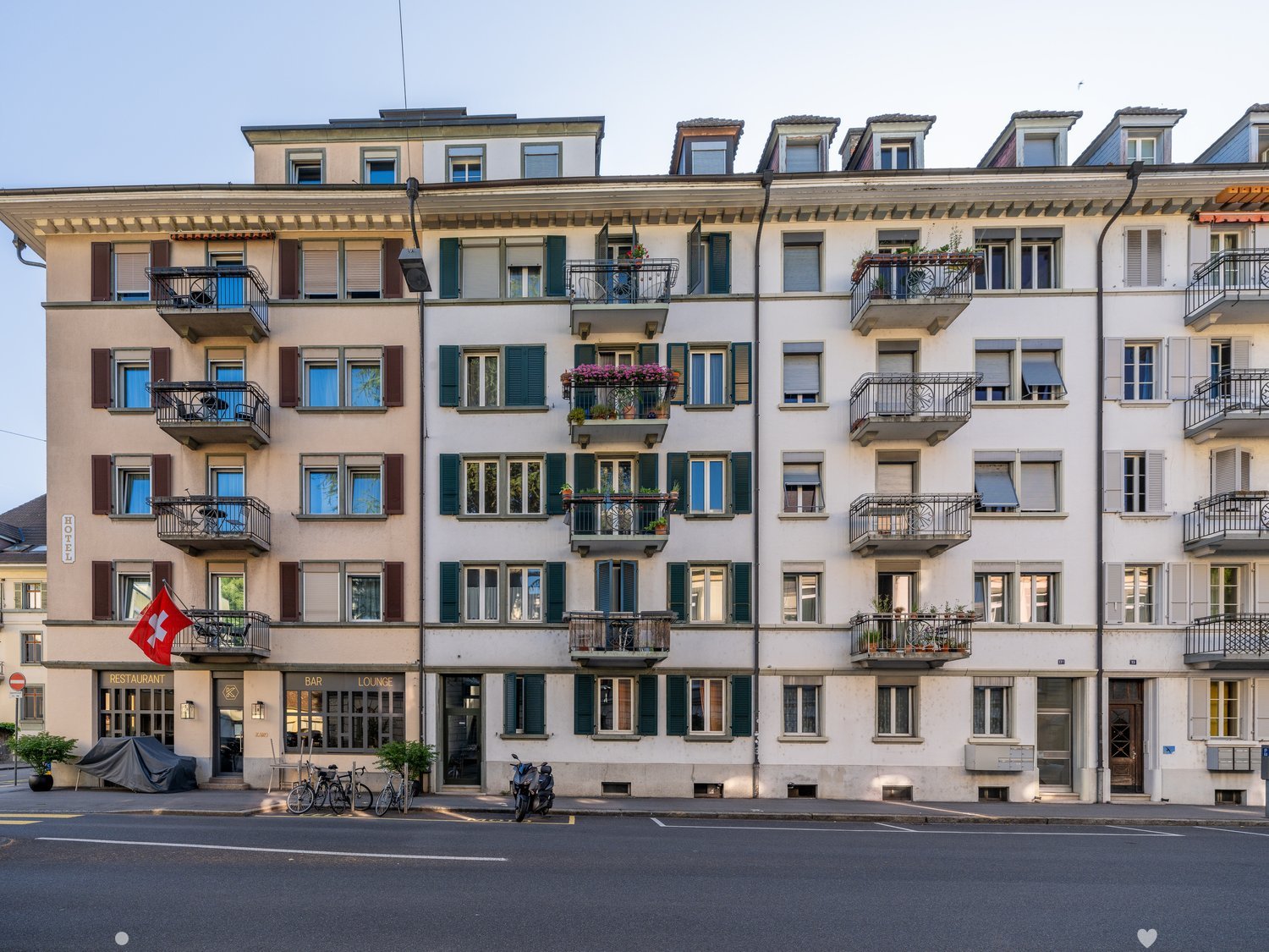 Modern building, multi story, white walls, balconies with railings, glass windows, potted plants