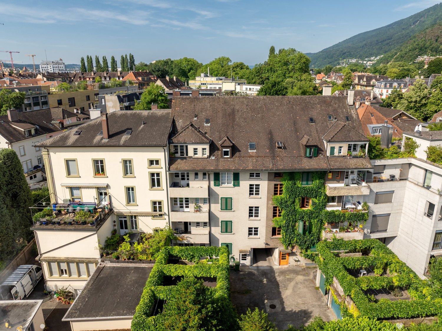multiple story building, greenery on terraces, large windows, visible balconies
