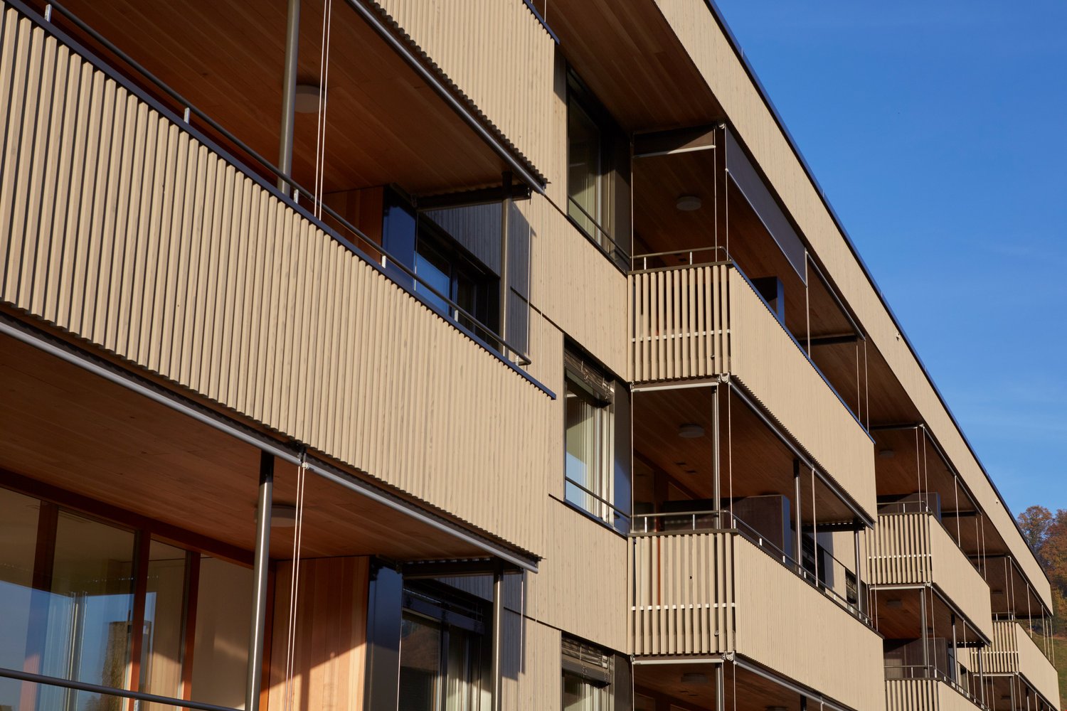 Modern architectural design, wooden and metal balconies, multiple floors, large windows