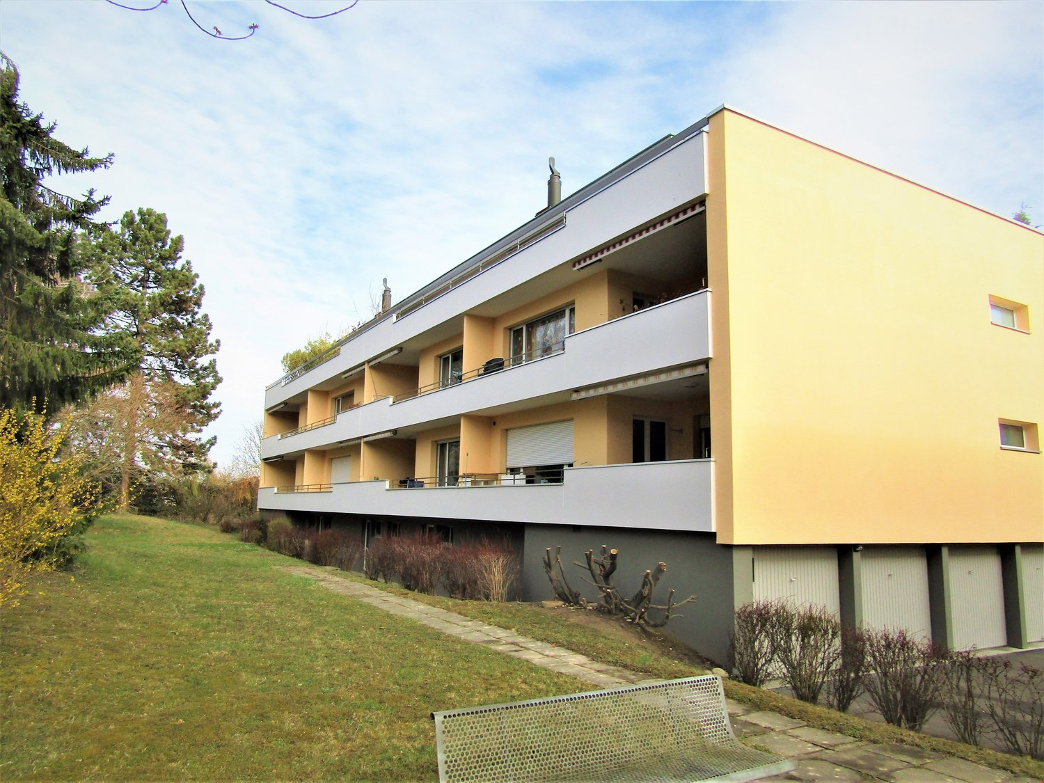 3 story apartment building, yellow and white, balconies, garage