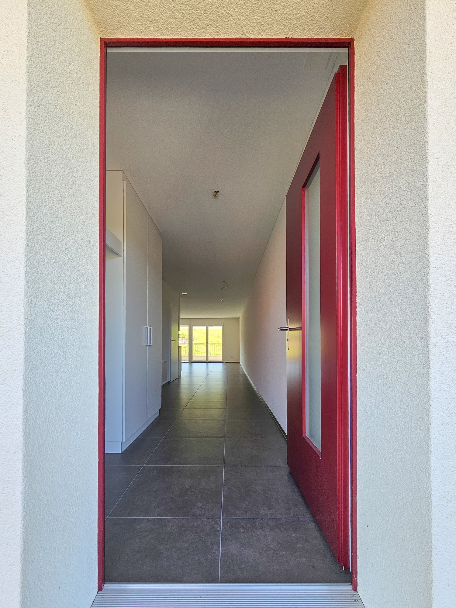 tiled floor, red door, white walls, glass doors at the end, lights on the ceiling