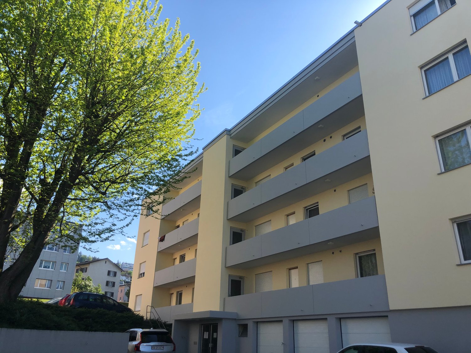 Yellow building, multiple stories, balconies, garage, modern architecture