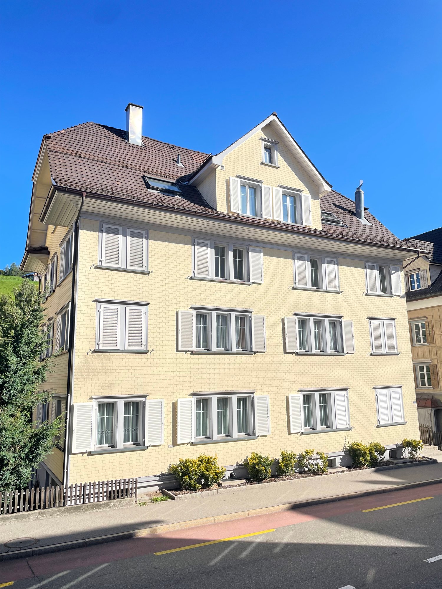 Multistory apartment building, yellow brick, white windows, brown roof, no visible features
