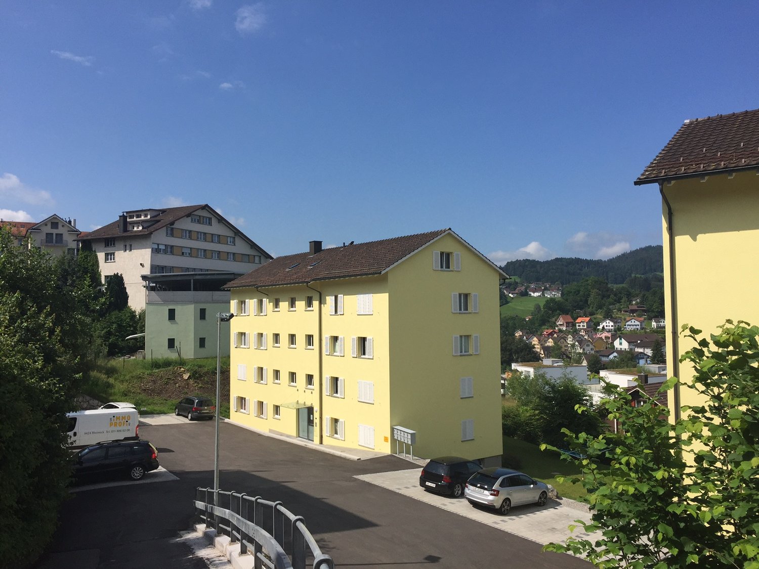 Yellow multistory building with parking area, street light, and several cars parked