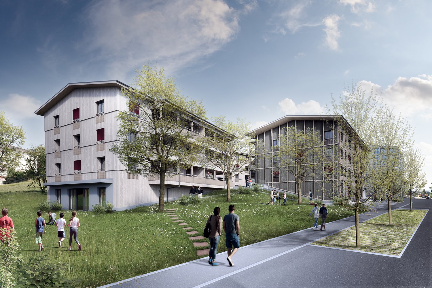 Modern residential complex with multiple buildings, elevated ground, grassy hills, and walking paths.