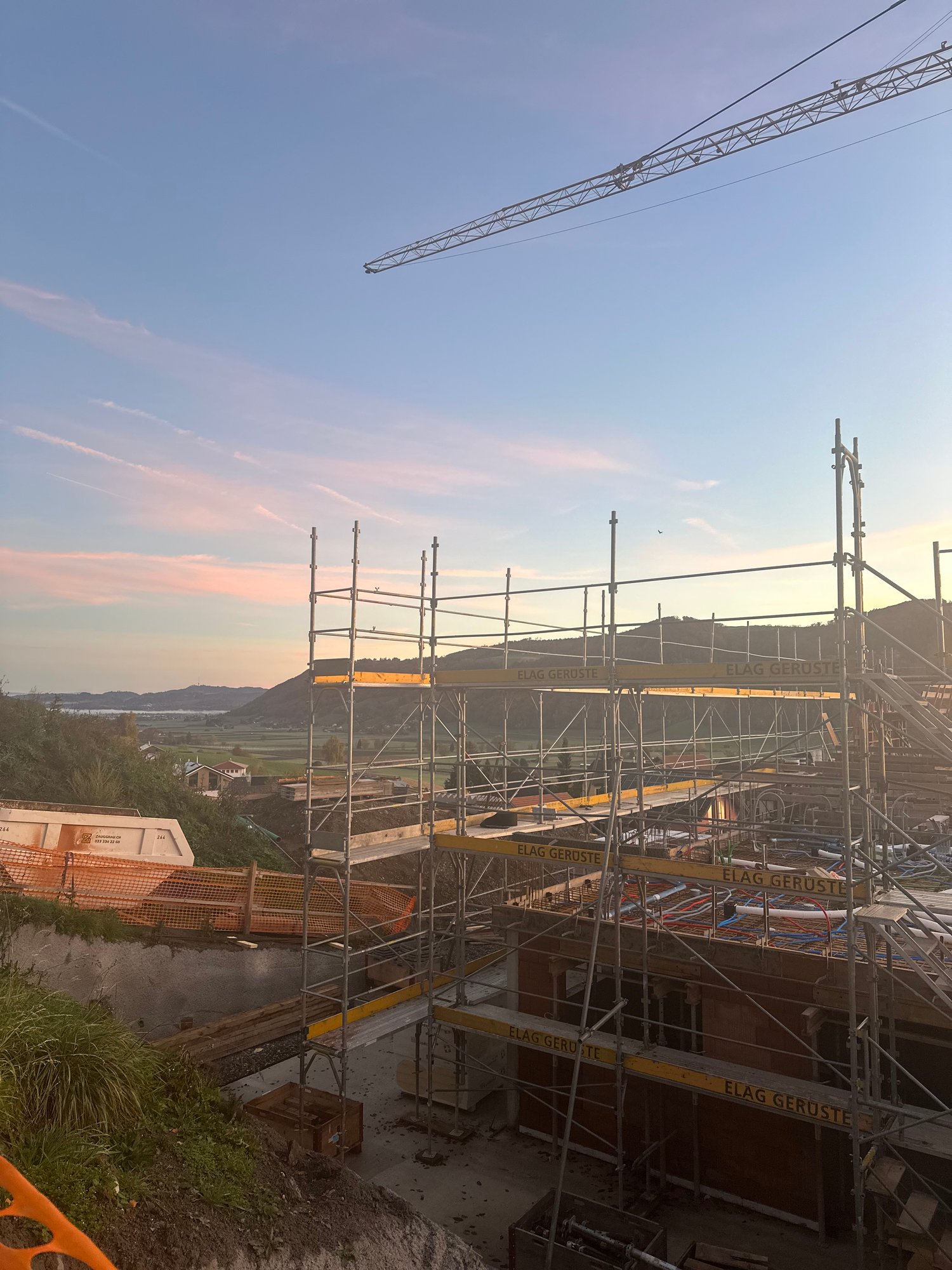 construction site with steel scaffolding, crane in the background, view of the mountains and horizon