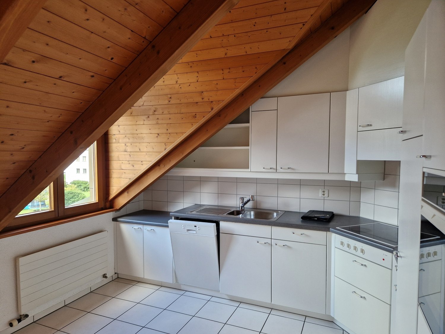 Wooden ceiling, white tiled floor, white cabinets, sink with faucet, dishwasher, window with external view, heating unit on wall