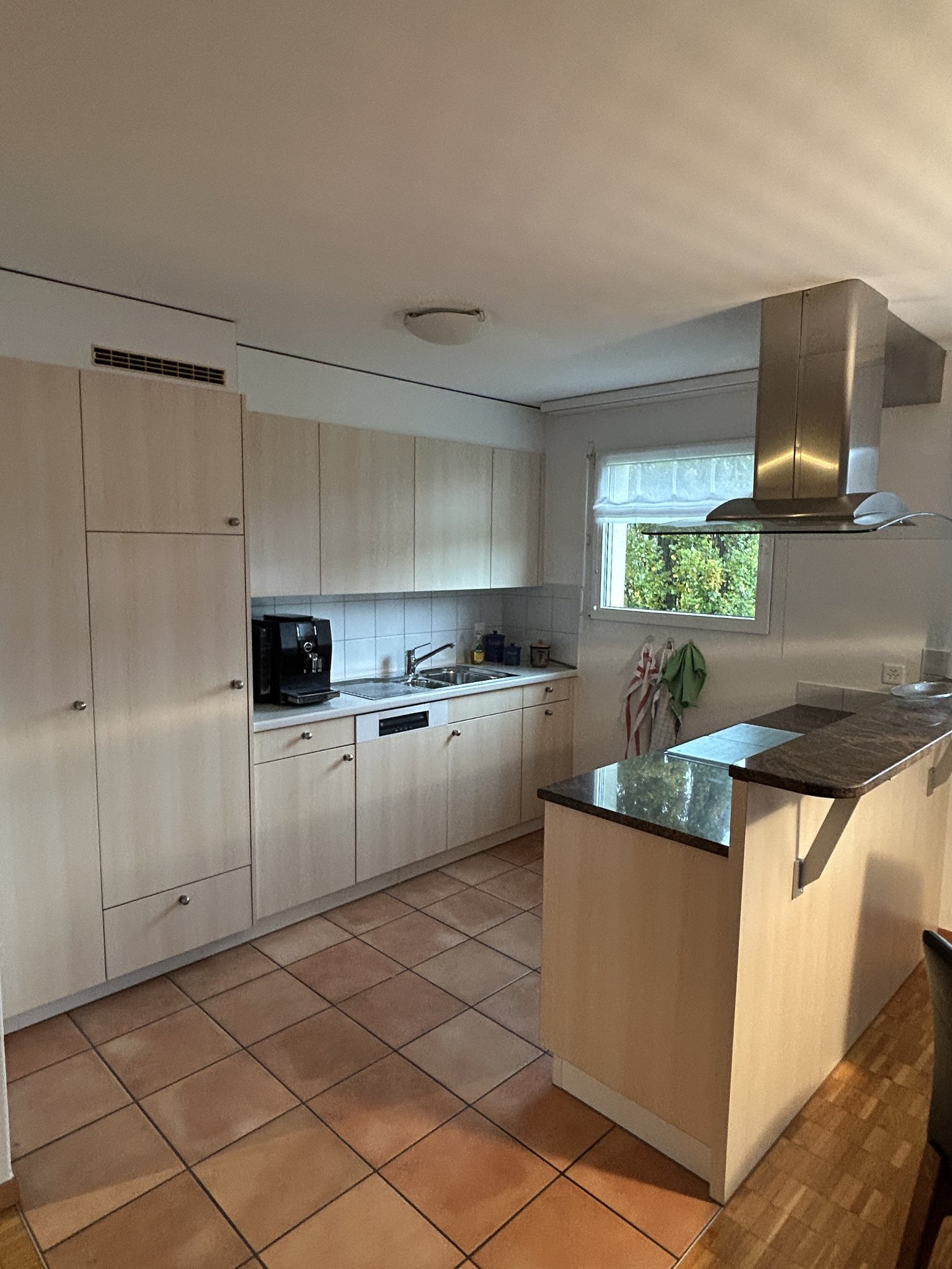 kitchen with wooden floor, built-in appliances, kitchen island, sink, dishwasher, window
