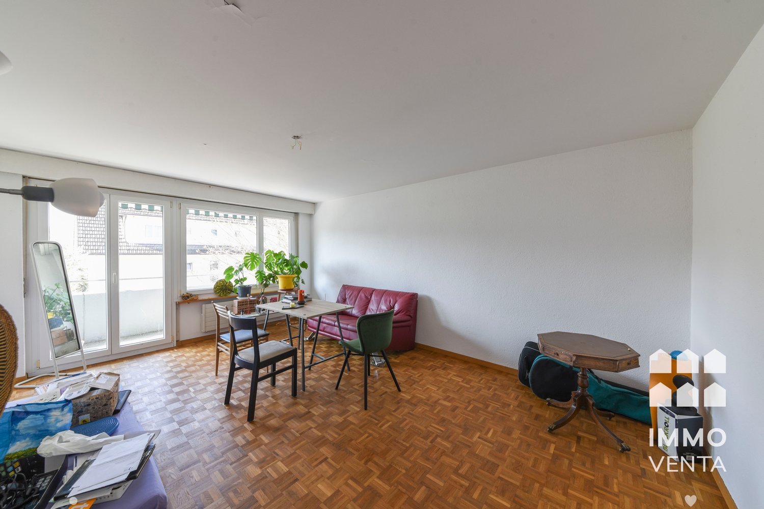wooden floor, white walls, large windows, sliding glass doors, balcony, table, chairs, couch, mirror, potted plants