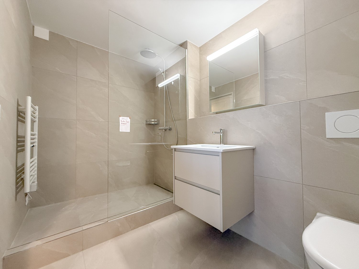 white tile walls, glass enclosed shower, white vanity with sink, mirror above vanity, toilet