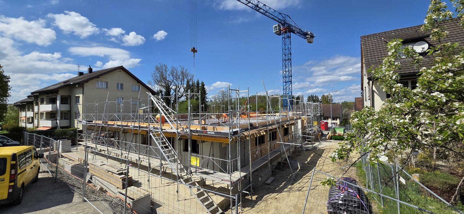 House under construction, scaffolding, crane, workers, yellow van, trees, houses, street light