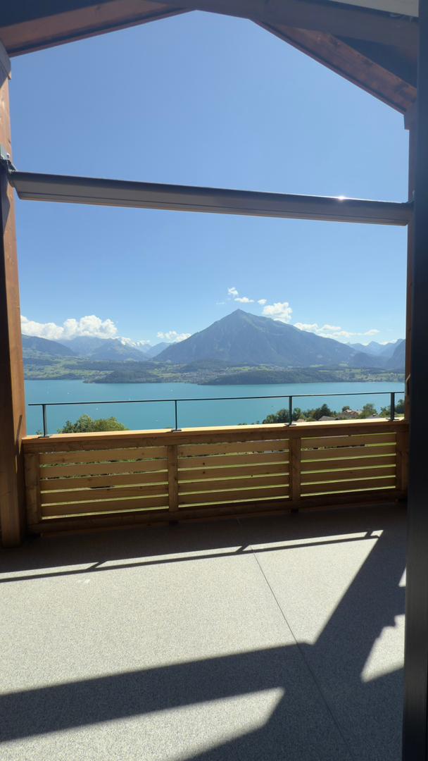 Wooden balcony with a view of a lake and mountains in the distance