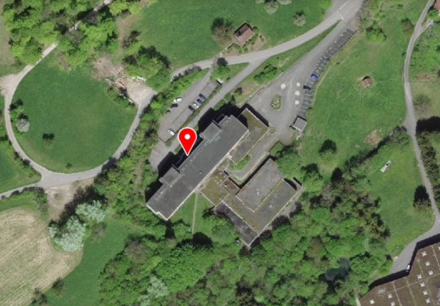 Large multi-story building with a parking lot in a rural, wooded area