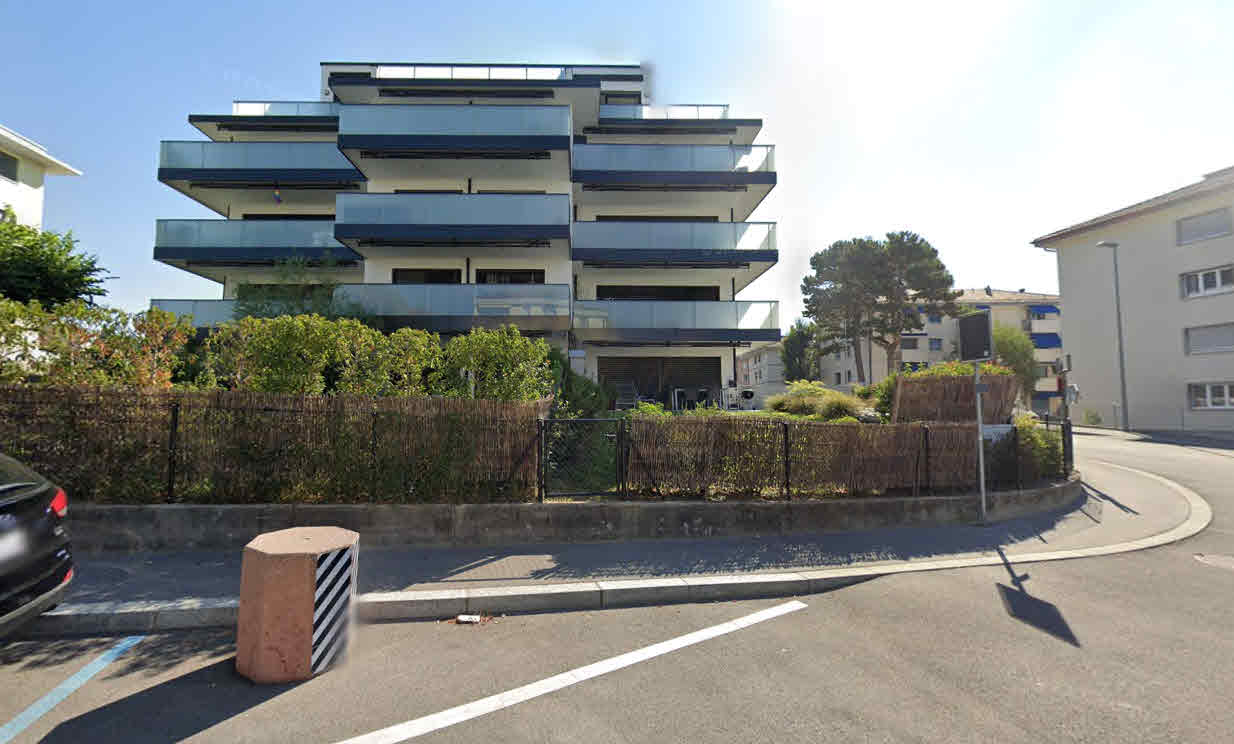 multi-story residential building, several balconies, paved road, parking space, fenced with greenery
