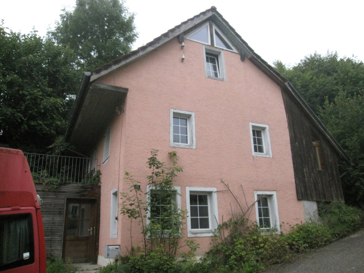 2 story house, pink walls, white windows, wooden section, door, mail box, plants, red van