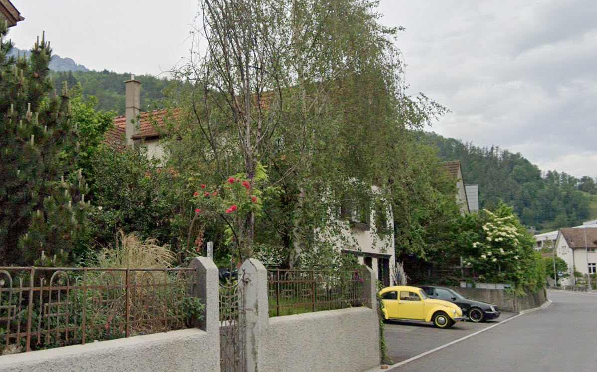 two story house, red roof, windows, yellow and black cars parked in front