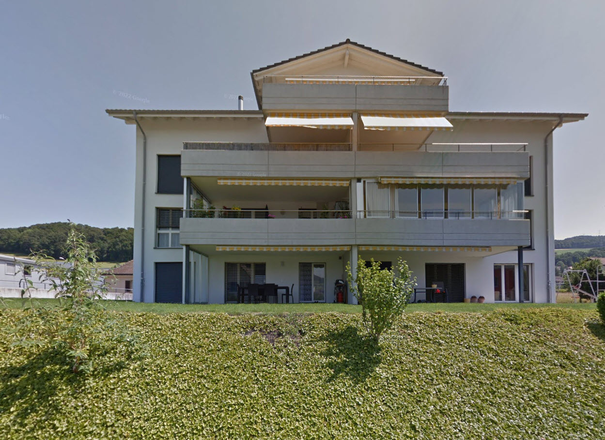 White modern house with 3 balconies and grassy front yard.