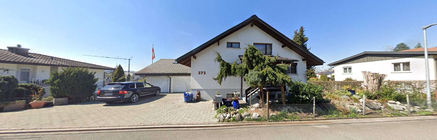 white two story house, black car parked, brown roof, two garages, garden