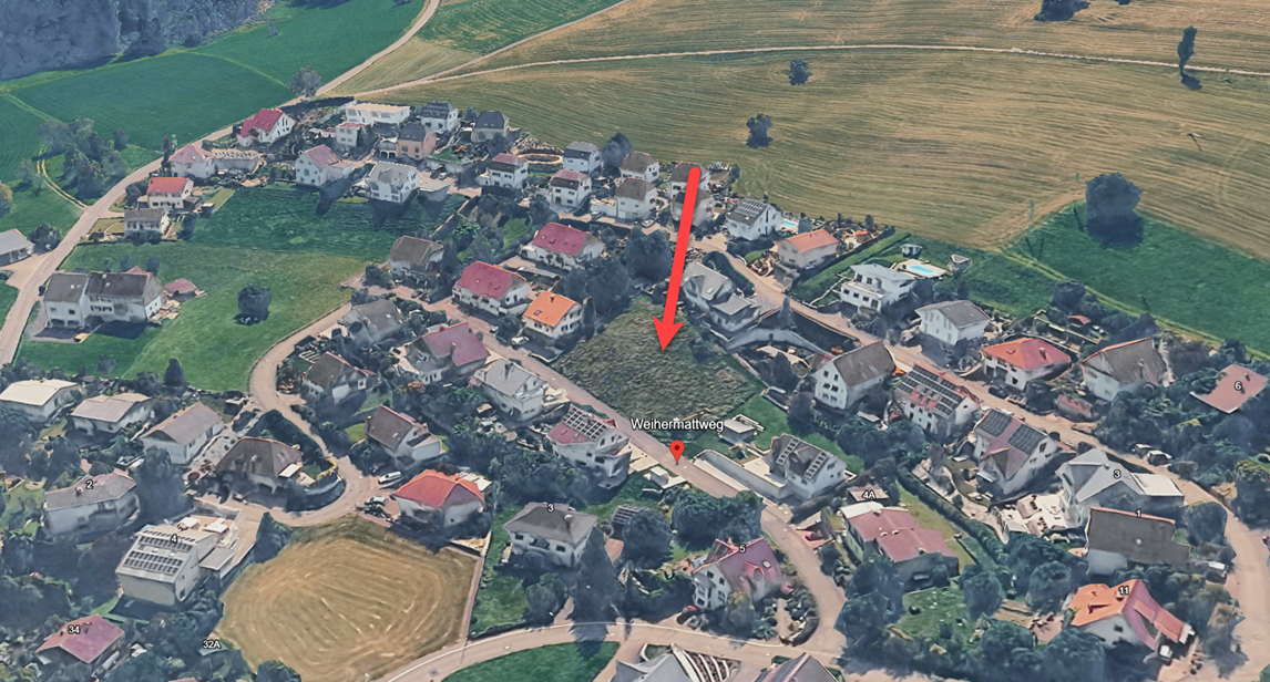 Aerial view of a residential area with several houses, a field, and a road.