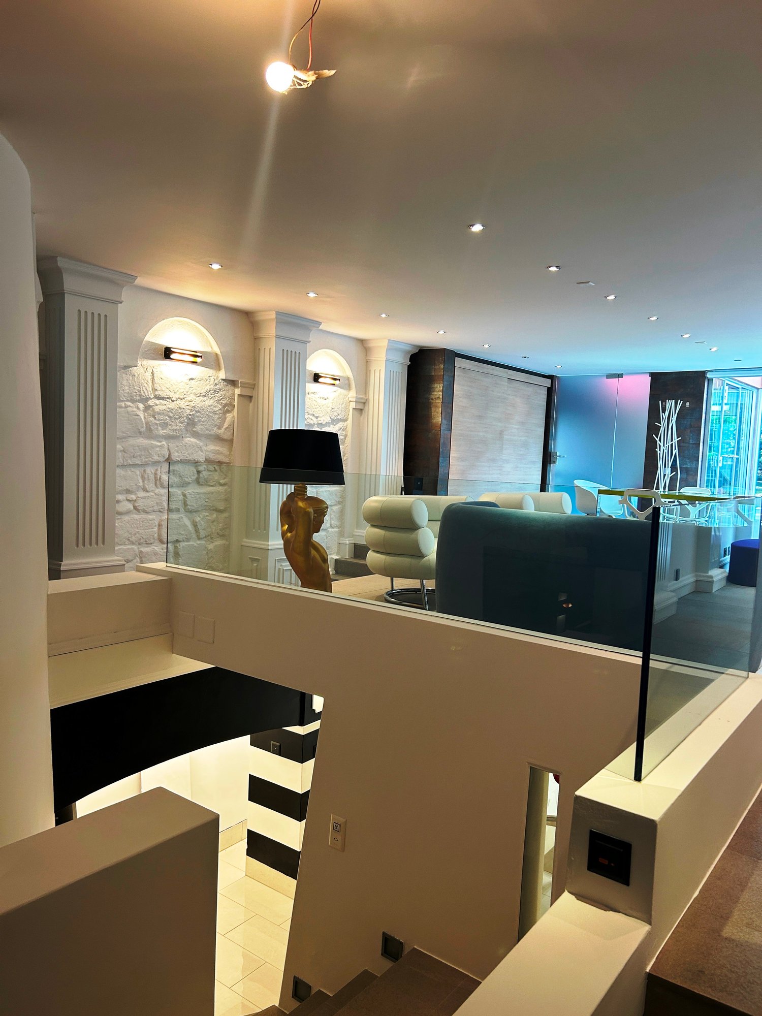 Spacious living room with modern decor, including a fireplace, arched windows, and a large sofa. The room has a mix of contemporary and traditional elements, with a stone accent wall and recessed lighting.