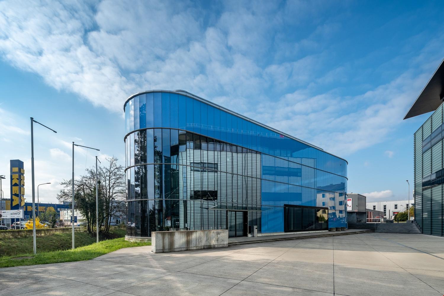 modern building with glass facade, blue panels, wide open area in front