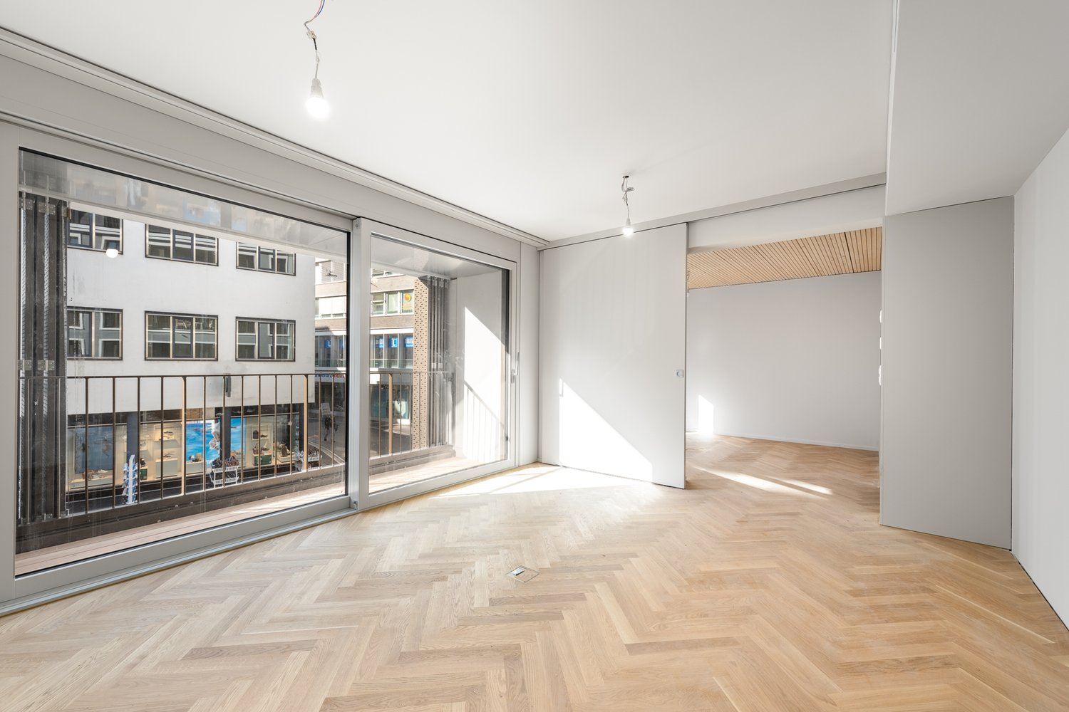 empty room, wooden parquet floor, large glass doors, balcony, white walls
